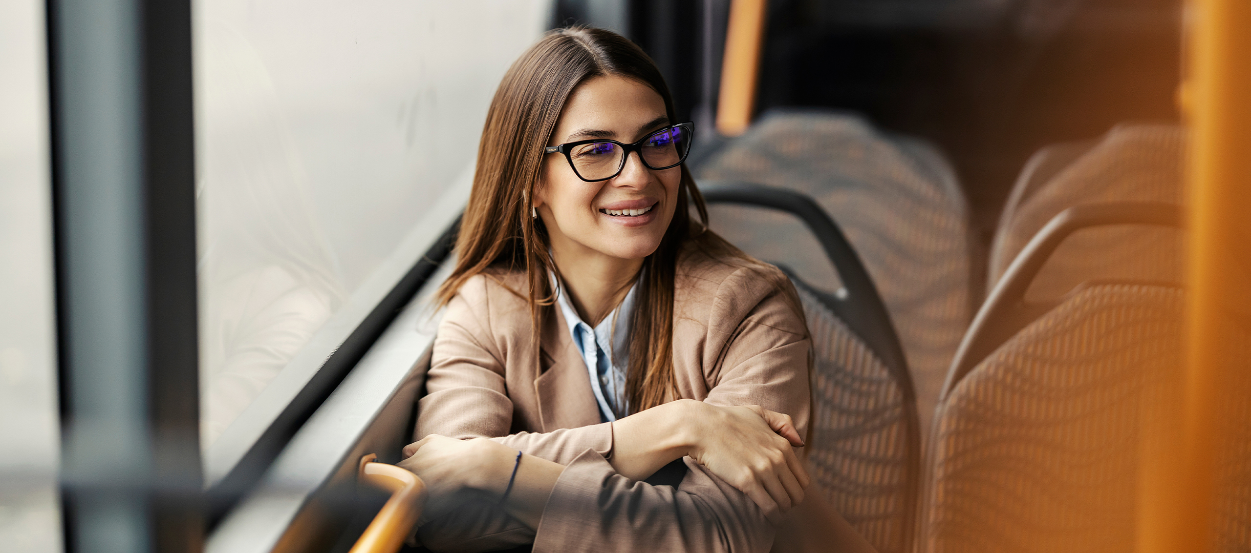 A women with glasses sitting on a bus