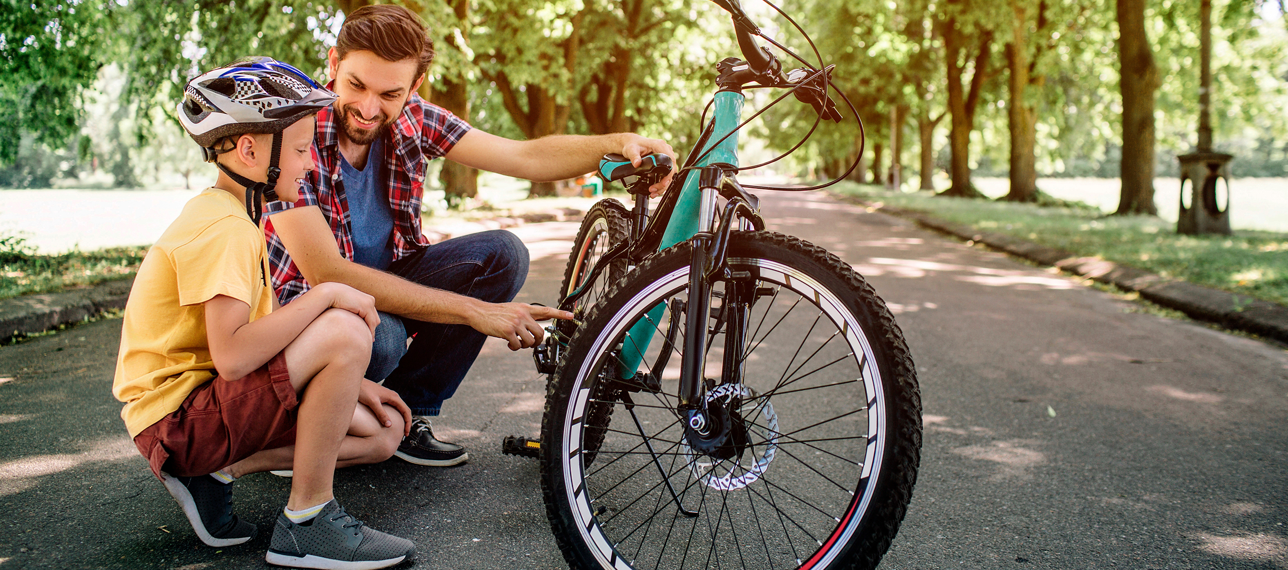 A father and son croushing down looking closely at a bike